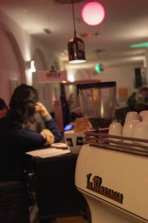 La Marzocco Espressomaschine im Vordergrund, unscharfer Barbetrieb im Hintergrund.