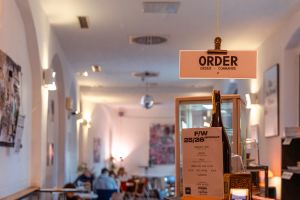 „Order“-Schild im Gang mit Blick in den tieferen Gastraum.