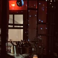 Bartheke mit Flaschen, Blumen und Kerzenlicht, Discokugel im Hintergrund