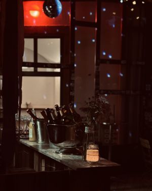 Bartheke mit Flaschen, Blumen und Kerzenlicht, Discokugel im Hintergrund