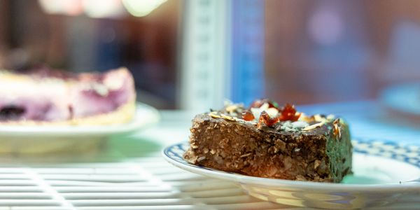 Schokoladiges Gebäckstück auf Teller in gekühlter Auslage.