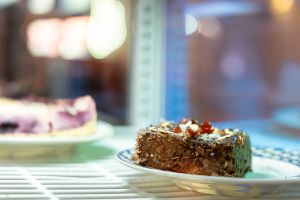 Schokoladiges Gebäckstück auf Teller in gekühlter Auslage.