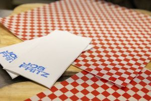 Rot-weiß kariertes Papier und Servietten mit blauem „Jos Fritz“ Stempel.