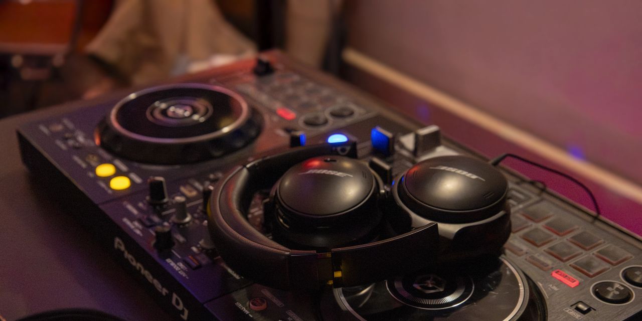 Nahaufnahme eines Pioneer DJ-Controllers mit schwarzen Bose-Kopfhörern.