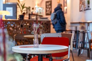 Tisch mit Trockenblumen und roten Stühlen im Café-Innenraum.