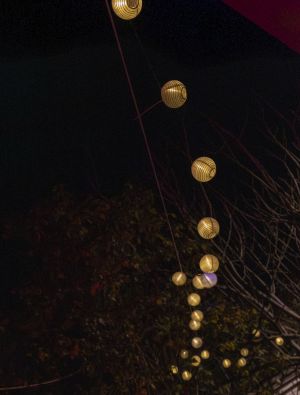 Lichterkette mit leuchtenden Lampions vor dunklem Nachthimmel.