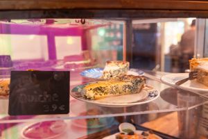 Quiche-Stücke mit Spinat auf Tellern in der Vitrine.